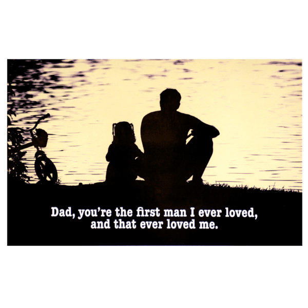 A father and his children sitting on the shore of a lake.