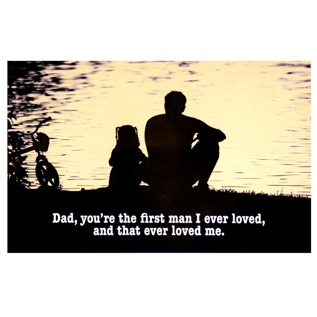 A father and his children sitting on the shore of a lake.