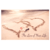 Two hearts drawn in the sand with a flower on top of it.