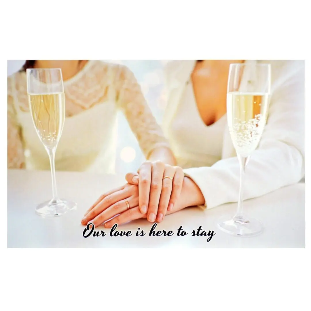 A couple holding hands with champagne glasses in front of them.