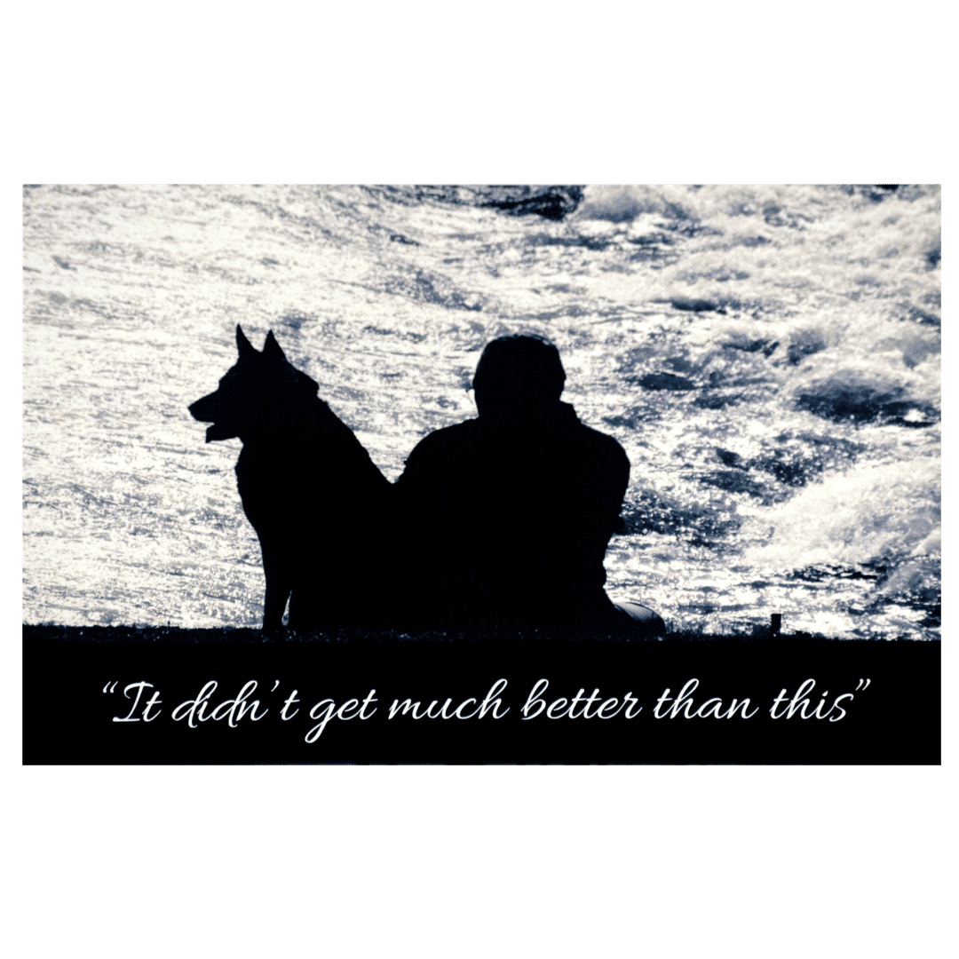 A man and his dog sitting in the grass.