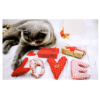 A cat laying on the ground with love spelled out in fabric.