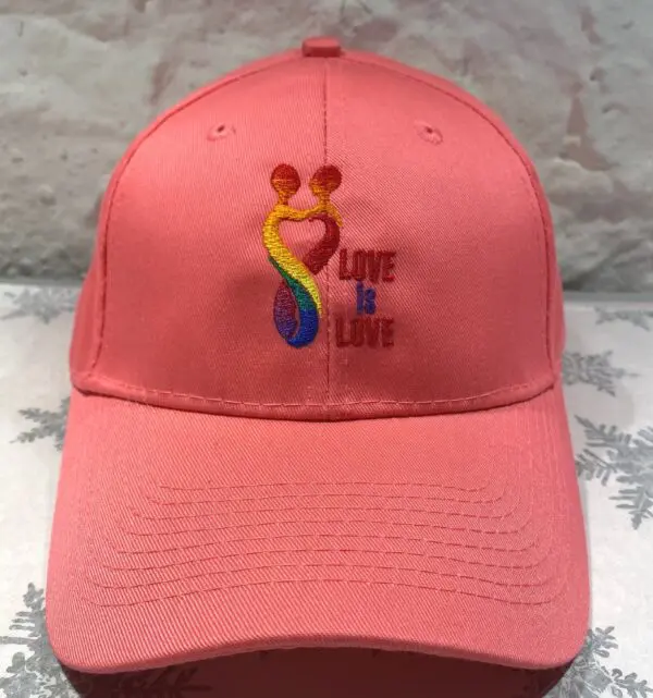 A pink hat with the words " love is love " embroidered on it.