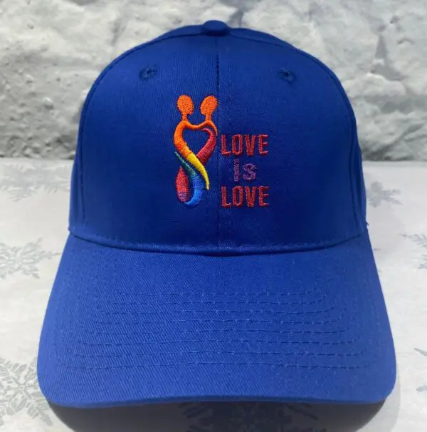 A blue hat with the words love is love embroidered on it.