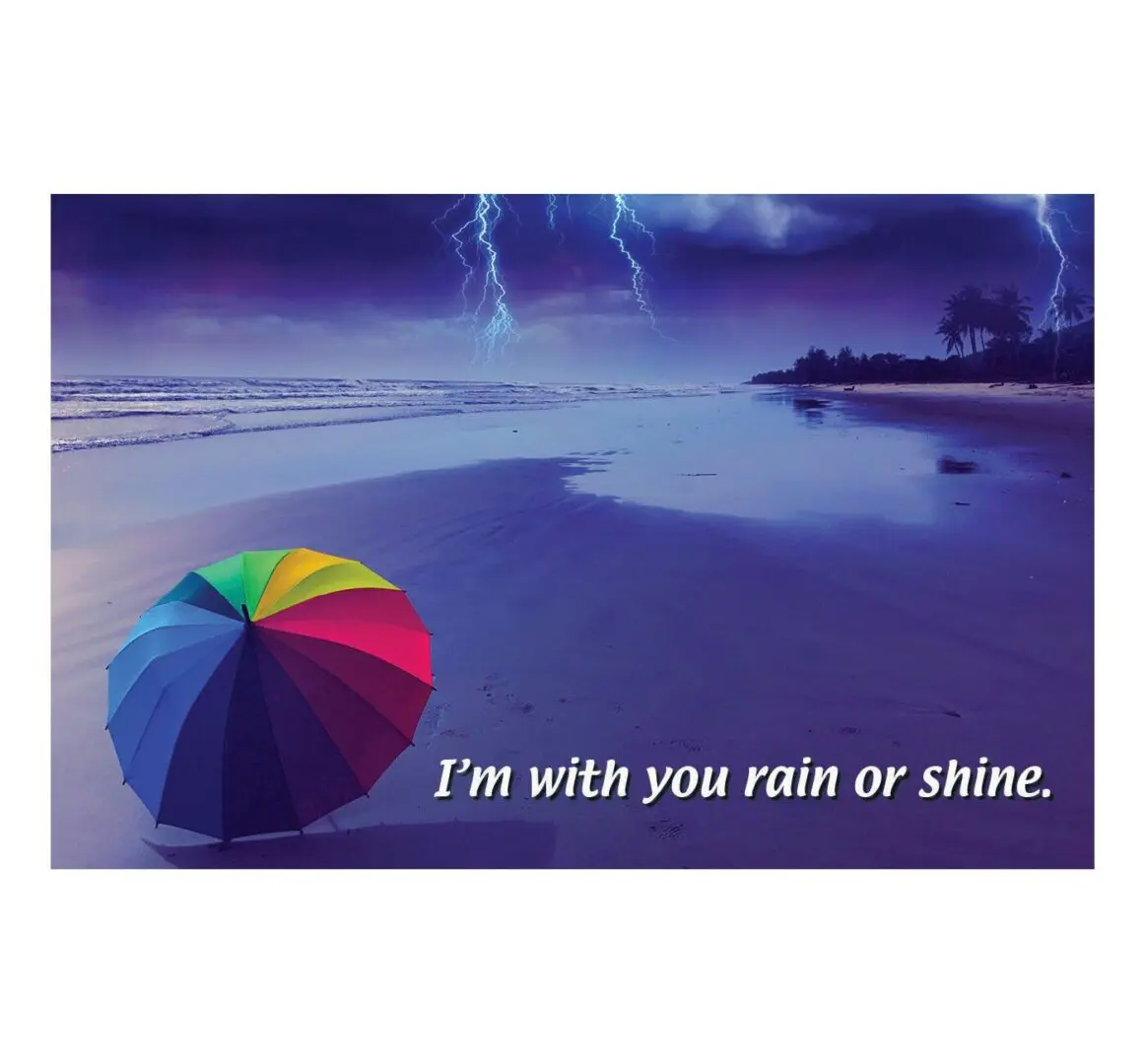 A rainbow umbrella on the beach with lightning in the background.