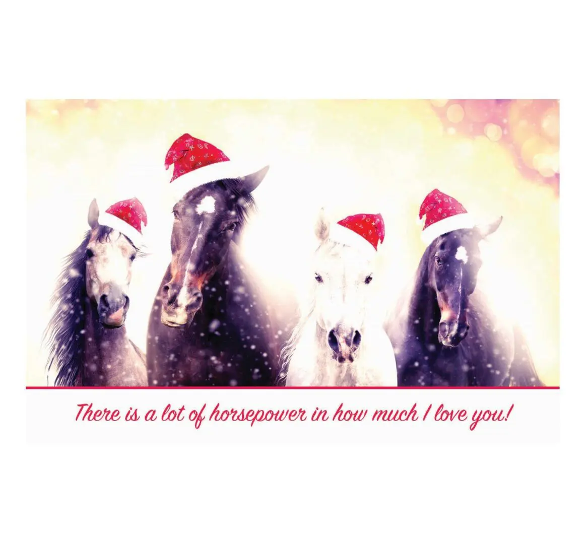 A group of horses wearing santa hats and standing in the snow.