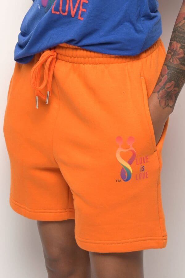 A person wearing orange shorts with rainbow symbols on them.