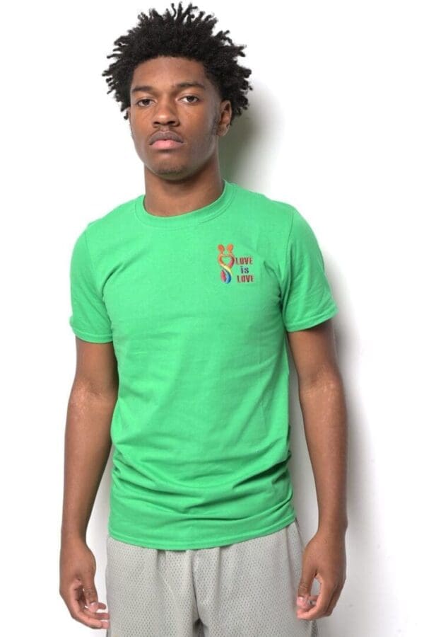 A man in green shirt standing next to wall.