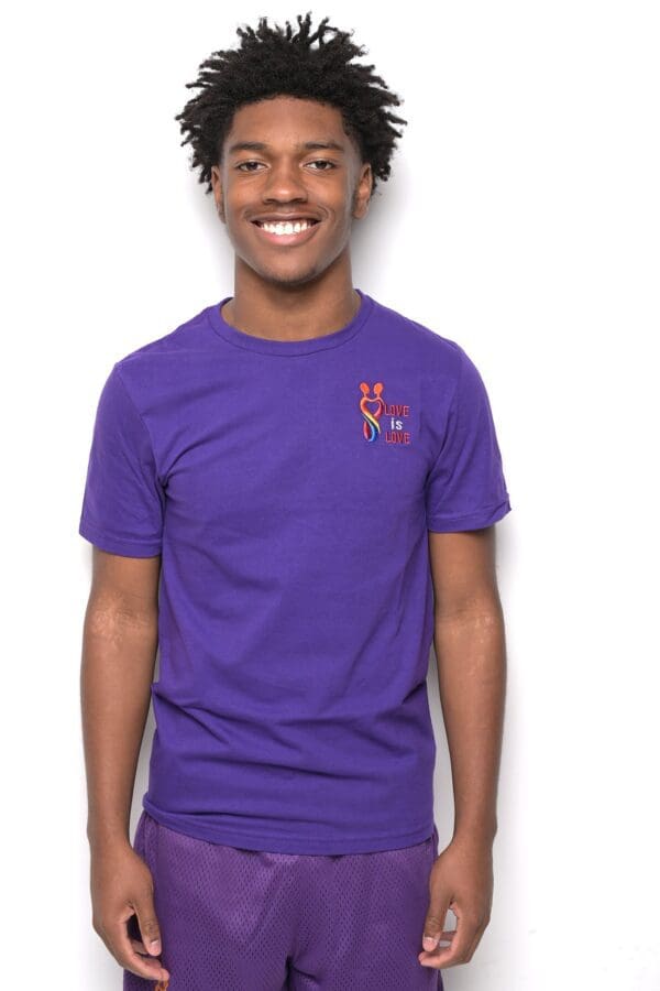 A man wearing purple shirt and smiling for the camera.