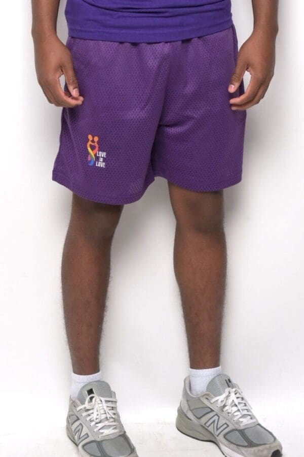 A man standing in front of the wall wearing purple shorts.