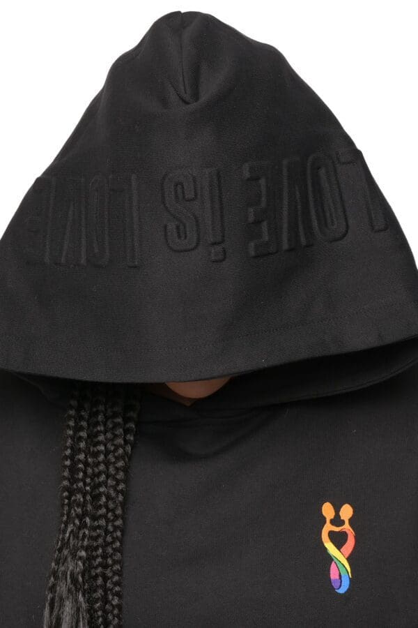 A person wearing a black hoodie with an orange logo.