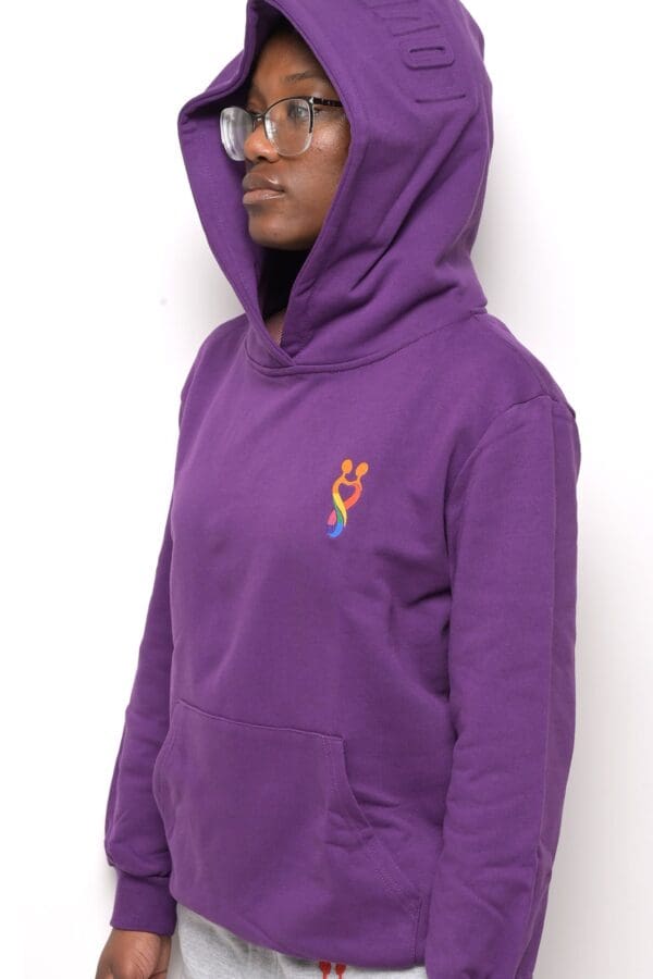 A person wearing a purple hoodie with a rainbow design on it.