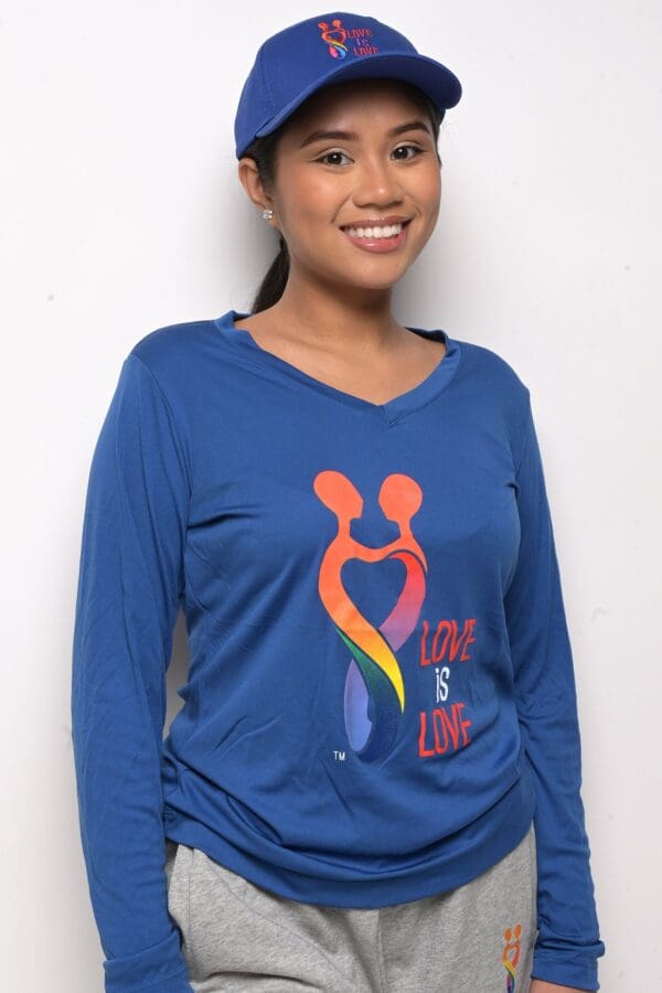 A woman wearing a blue shirt with a rainbow heart on it.