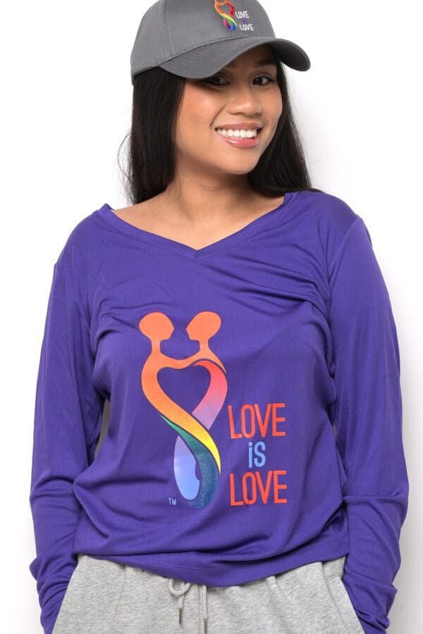 A woman wearing a purple shirt with the words " love is love ".