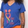 A woman wearing an orange and blue shirt with the words " love is love ".