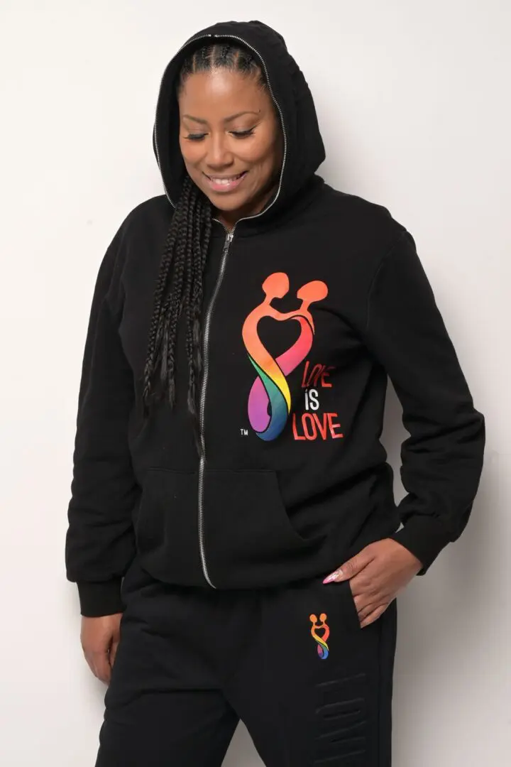 A woman wearing a black hoodie and holding her phone.