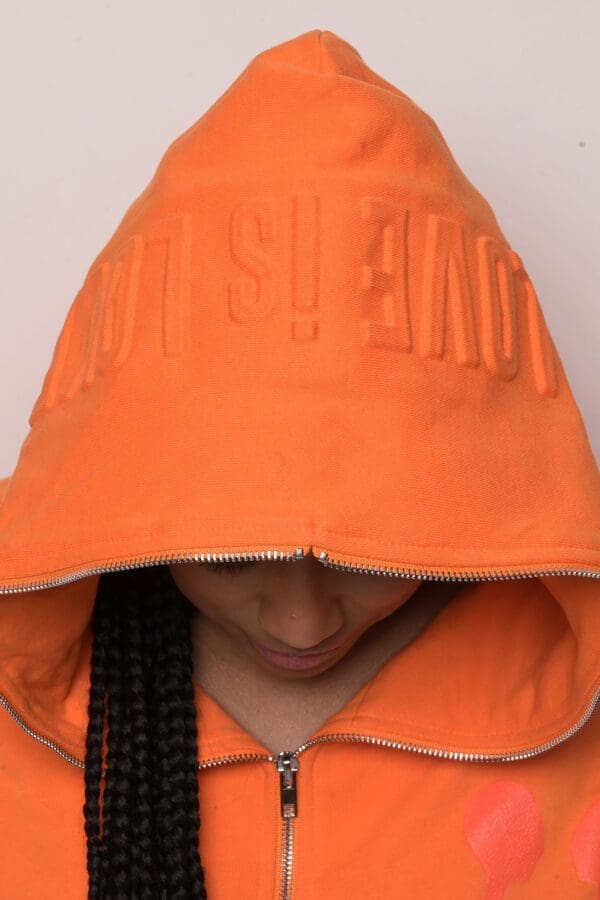 A person wearing an orange jacket with the word " supreme " written on it.