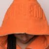 A person wearing an orange jacket with the word " supreme " written on it.