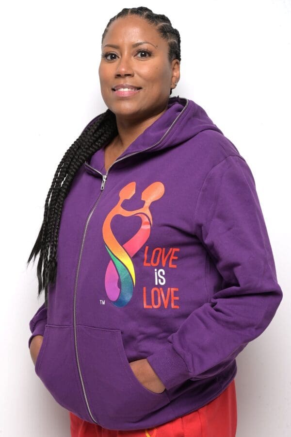 A woman wearing purple hoodie with rainbow heart and love is love on it.